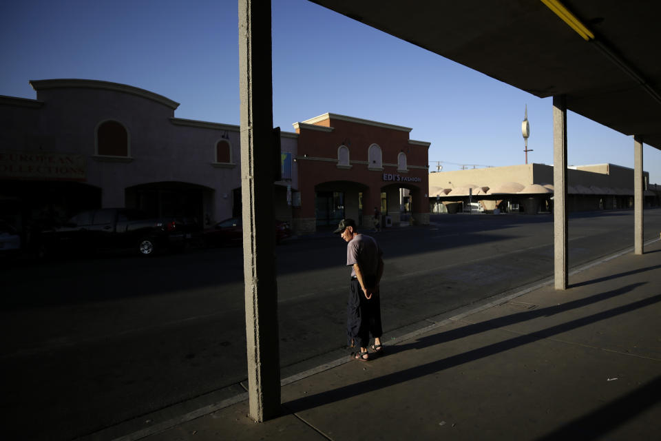 Clothing store owner Teeyung Chang looks out on empty streets Tuesday, July 21, 2020, in Calexico, Calif. Forced to shut his doors to shoppers as the coronavirus cases surged, Chang is unsure if his Divas Fashions store will survive. (AP Photo/Gregory Bull)
