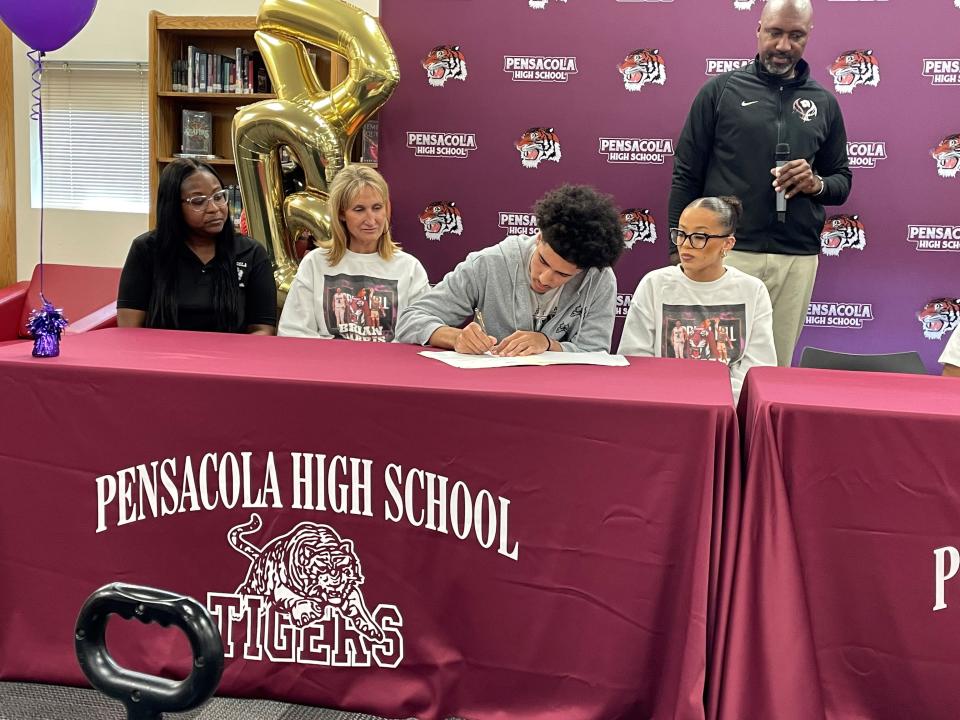Pensacola High senior Brian Harris (center right) signs his letter of intent to play basketball at Spring Hill College during a signing ceremony on Thursday, April 13, 2023 at Pensacola High School.