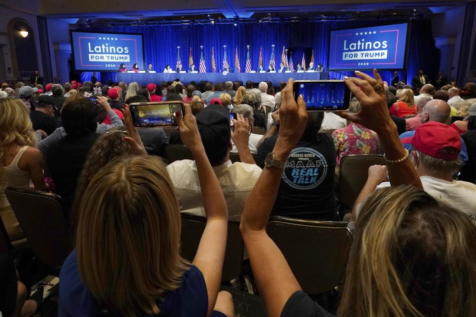 People in the crowd take pictures as President Donald Trump participates in a Latinos for Trump Coalition roundtable campaign event Monday, Sept. 14, 2020, in Phoenix. (AP Photo/Ross D. Franklin)