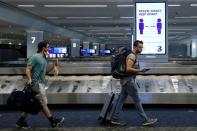 FILE PHOTO: Travelers pass a sign alerting them to distance at LaGuardia Airport, during the outbreak of the coronavirus disease (COVID-19), in New York