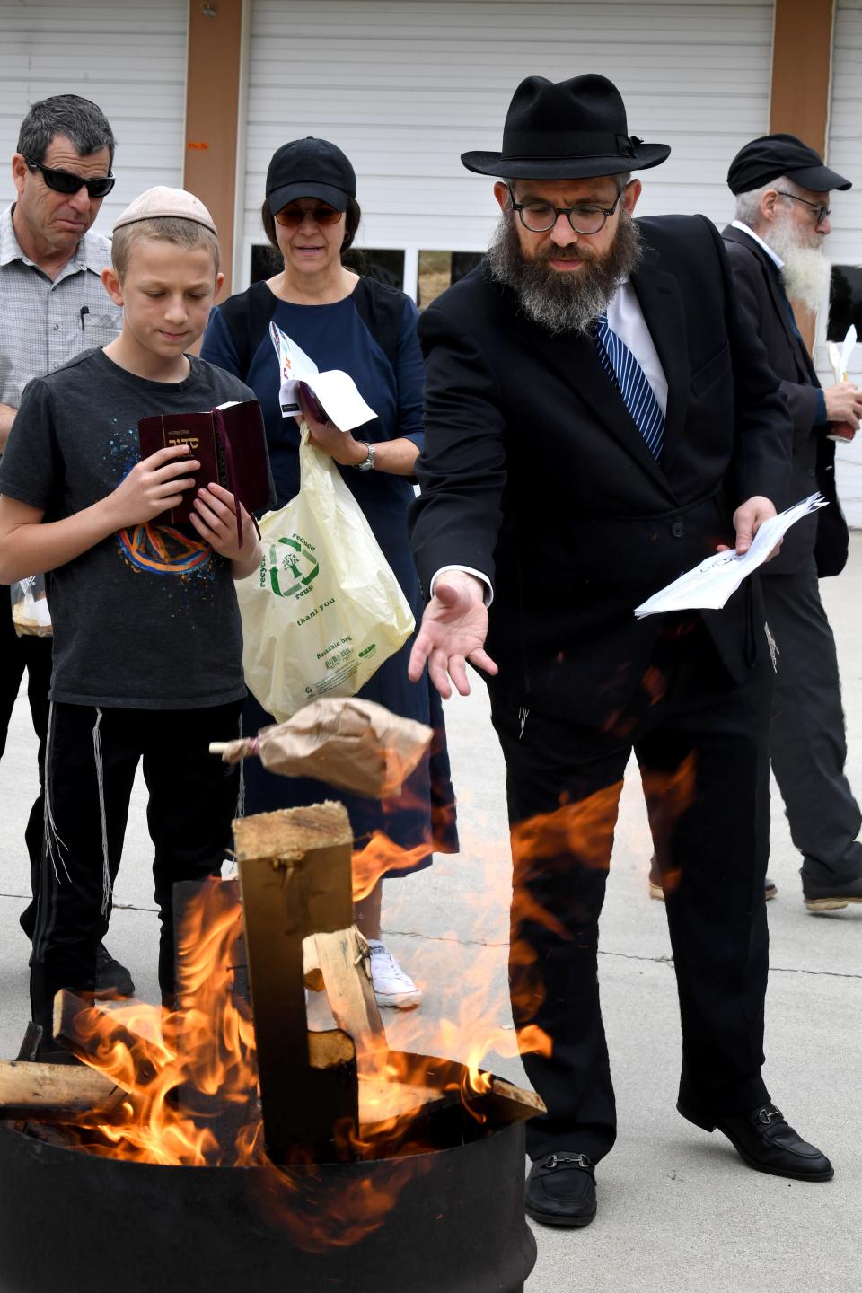 Rabbi Aryeh Lang of Chabad of Camarillo tosses a bag of bread into a fire pit at Ventura County Fire Station No. 52 in Camarillo as community members participate in an annual bread burning ceremony as part of the Jewish observance of Passover on Monday.