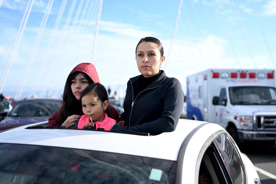 Elsa Santos and her children wait for police officers to clear protesters off the San Francisco-Oakland Bay Bridge during a demonstration against the APEC summit on Thursday, Nov. 16, 2023, in San Francisco. Santos was stuck for several hours while trying to take her kids to school. (AP Photo/Noah Berger)