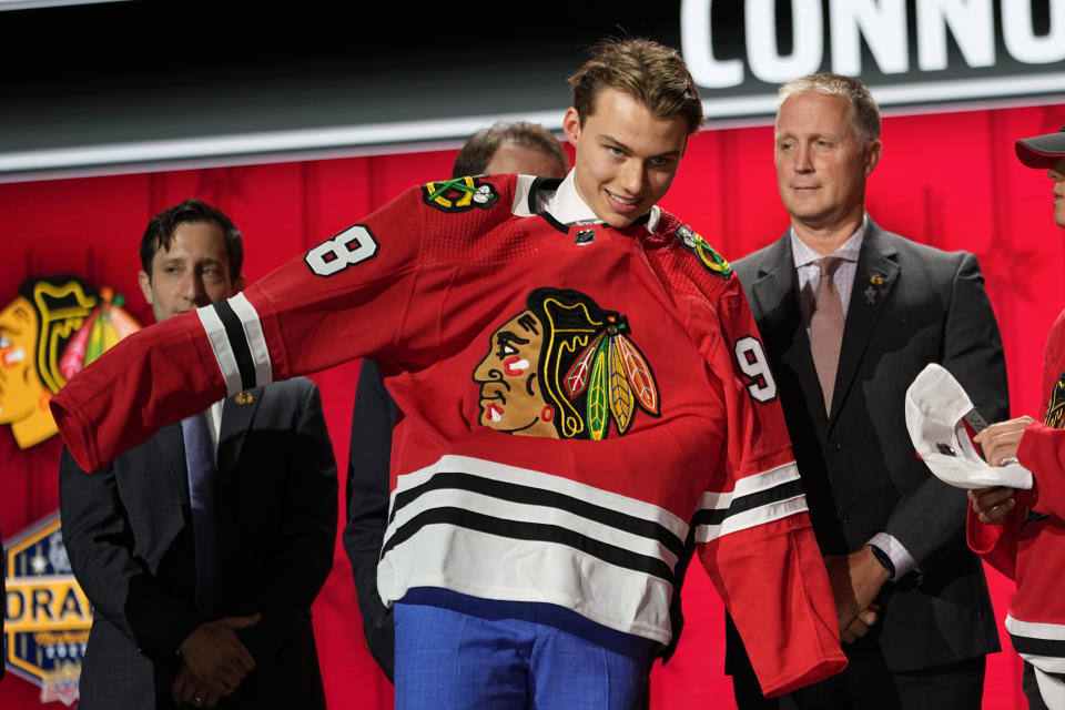 Chicago Blackhawks first round draft pick Connor Bedard puts on his jersey after being picked by the team during the first round of the NHL hockey draft, Wednesday, June 28, 2023, in Nashville, Tenn. (AP Photo/George Walker IV)