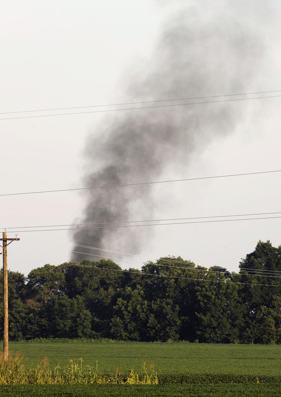 FILE - In this July 10, 2017, file photo, smoke rises in the air after a military transport plane crashed into a field near Itta Bena, Miss., on the western edge of Leflore County, as seen from U.S. Highway 82. Investigators say bad maintenance practices at a Georgia air force base missed a deteriorating propeller blade that broke off six years later as a U.S. Marine Corps transport plane cruised over Mississippi at 20,000 feet, causing the KC-130T to break into pieces and plunge into a soybean field, killing 15 Marines and a Navy corpsman, according to the report on the causes of the July 10, 2017, crash, released Wednesday, Dec. 5, 2018. (AP Photo/Andy Lo, File)