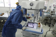 A healthcare worker wearing full protective gear looks at the chest X-ray of a patient in a ward reserved for COVID-19 patients at the Hospital Juarez, in Mexico City, Friday, June 26, 2020. Mexico ranks seventh globally in COVID-19 deaths and third in its mortality rate among the 20 currently most affected countries, according to Johns Hopkins University. (AP Photo/Eduardo Verdugo)