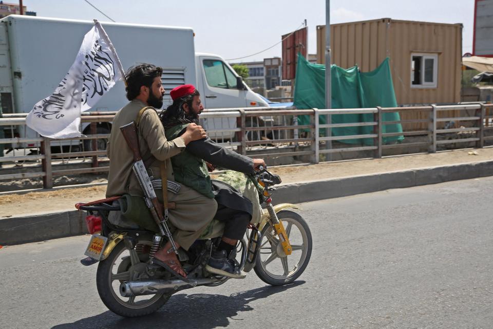 Taliban fighters ride a motorbike along the street in Kabul on August 16, 2021, after a stunningly swift end to Afghanistan's 20-year war, as thousands of people mobbed the city's airport trying to flee the group's feared hard-line brand of Islamist rule. (-/AFP via Getty Images) 