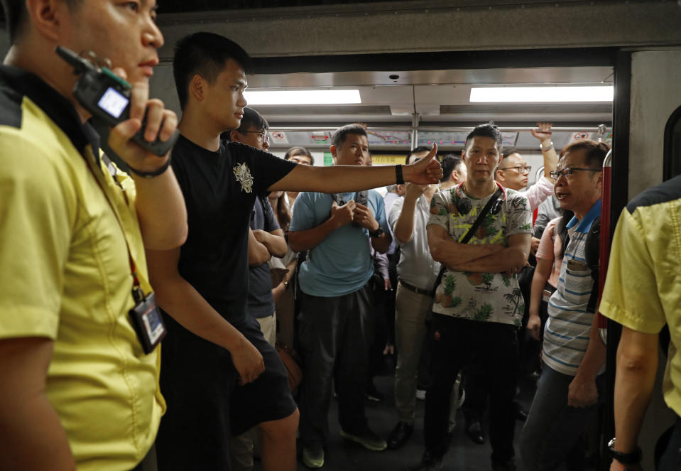 A protester in black shirt gestures against some passengers as he blocked the train doors stopping the trains leaving at a subway platform in Hong Kong Wednesday, July 24, 2019. Subway train service was disrupted during morning rush hour after dozens of protesters staged what they called a disobedience movement to protest over a Sunday mob attack at a subway station. (AP Photo/Vincent Yu)