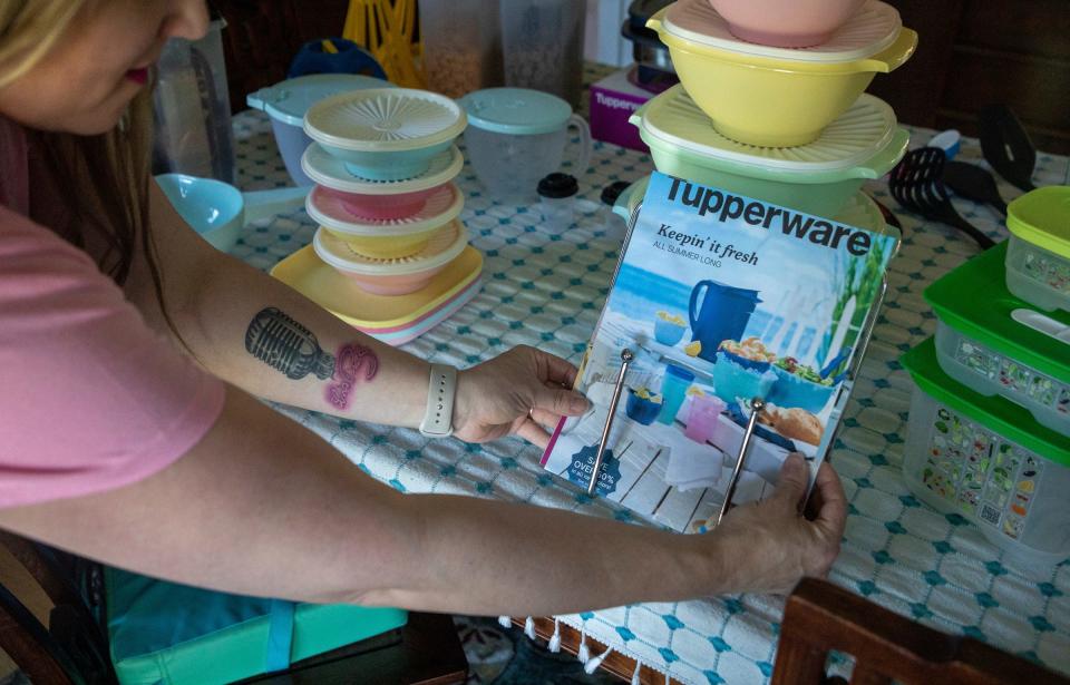 Janet Henriksen Lloyd, a Tupperware consultant and stay-at-home mother of four, organizes a Tupperware summer catalog on her kitchen table in Davison on Friday, May 26, 2023. 