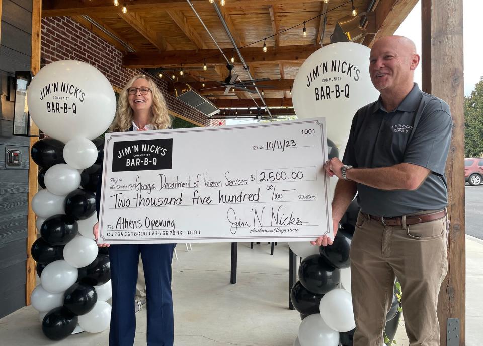 (L-R) Georgia Department of Veteran Services commissioner Patricia Ross is presented with a $2,500 check by Jim 'N Nick's Community Bar-B-Q president and COO Brian Lyman at the grand opening of the restaurant's Athens, Ga. location on Wednesday, Oct. 11, 2023.