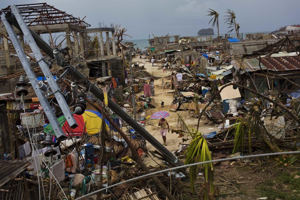 FILE - In this Nov. 14, 2013 file photo, Typhoon Haiyan survivors walk through ruins in the village of Maraboth, in the Philippines. Last year was tied for the fourth warmest year on record around the world. The National Oceanic and Atmospheric Administration on Tuesday released its global temperature figures for 2013. The average world temperature was 58.12 degrees (14.52 Celsius) tying with 2003 for the fourth warmest since 1880.(AP Photo/David Guttenfelder)