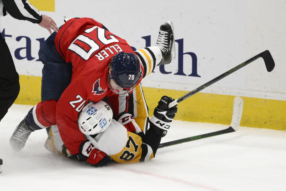 Washington Capitals center Lars Eller (20) takes down Pittsburgh Penguins center Sidney Crosby (87) during overtime of an NHL hockey game, Thursday, Jan. 26, 2023, in Washington. The Capitals won 3-2 in a shootout. (AP Photo/Nick Wass)
