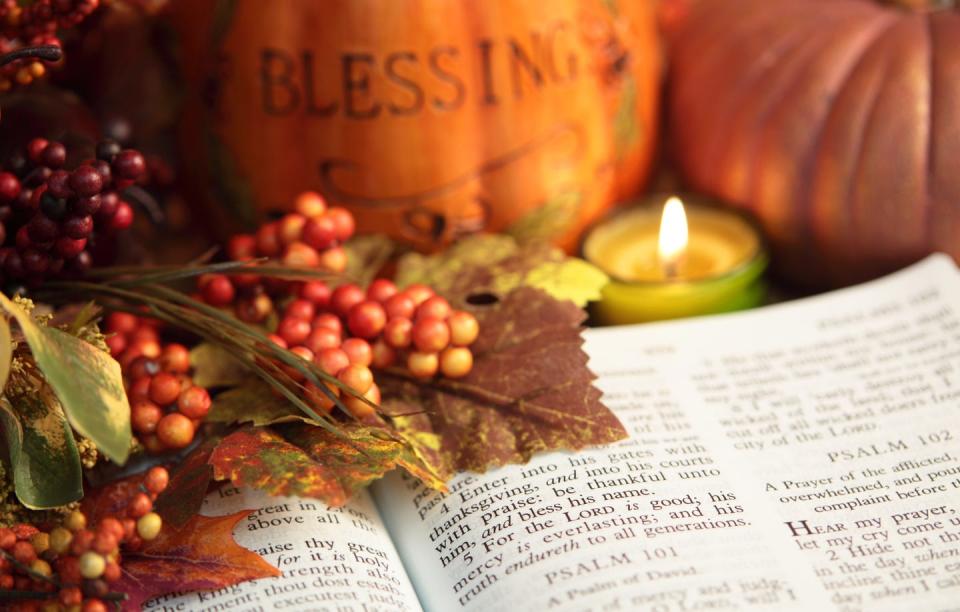 open bible showing scripture psalms 101 with autumn colored berries, leaves and candle there are two pumpkins in background, one pumpkin is inscribed with blessings