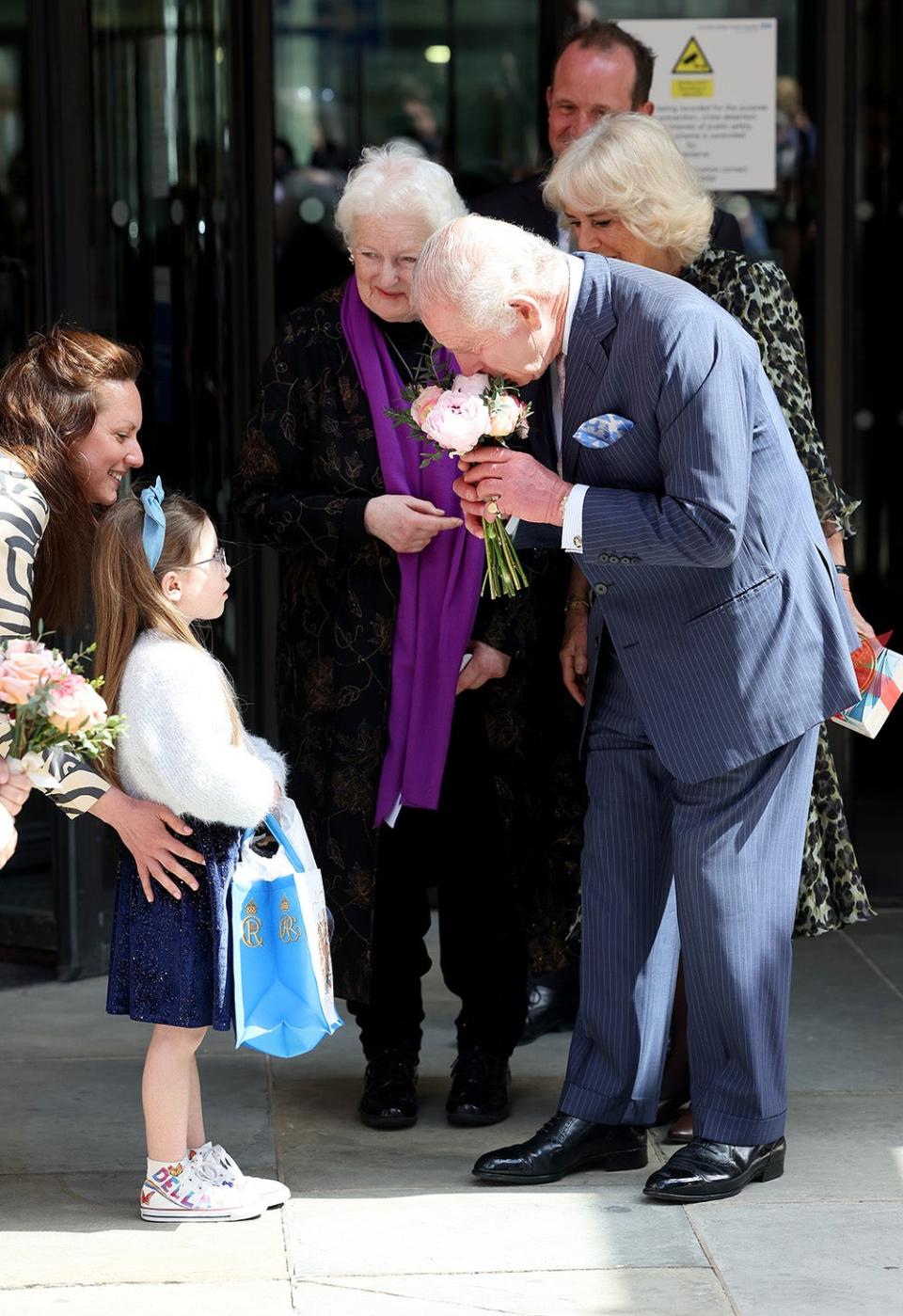 King Charles smelling flowers given to him by a little girl