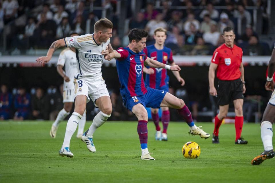 El jugador de Barcelona Robert Lewandowski (der.) lucha por el balón con Toni Kroos, del Real Madrid, en el partido celebrado el 21 de abril de 2024 en el Estadio Santiago Bernabéu de la capital española.
