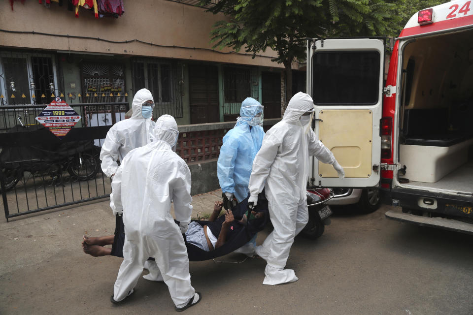 Izhaar Hussain Shaikh, left, an ambulance driver who works for HelpNow, an initiative to help the stretched services of first responders, and others pick up a COVID-19 patient from his home in Mumbai, India May 28, 2020. Shaikh's daily shifts are grueling, sometimes stretching to 16 hours. (AP Photo/Rafiq Maqbool)