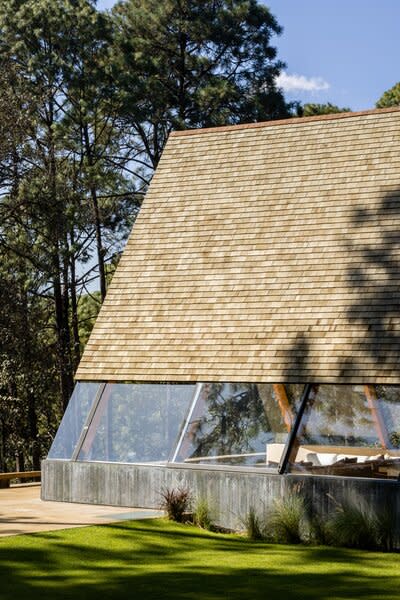 The extended section of the A-frame continues with cedar shingles and large glass panels for its lower half.