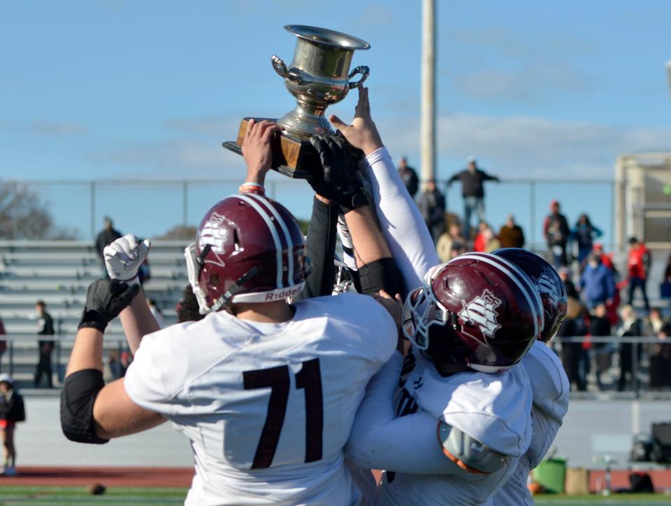 HYANNIS -- 11/24/22 -- Falmouth players hoist their winning trophy into the air after beating Barnstable 25-19. 
Barnstable High School hosted Falmouth High School in Thanksgiving Day football action. Falmouth won 25-19.