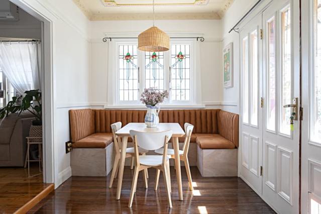 Contemporary minimalist style interior design of light studio apartment  with wooden table and chairs in dining zone between open kitchen and living  room with white walls and parquet floor Stock Photo 