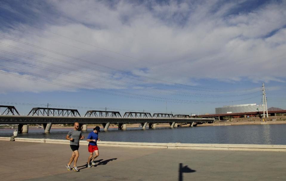 A couple jogs along Tempe Town Lake, Monday, Nov. 26, 2012 in Tempe, Ariz. With cactus and strip malls obstructing the view at times, visitors could easily write Phoenix off as a place where water and culture are scarce. But this metropolis _ which includes upscale Scottsdale and college town Tempe _ is a nature lover's oasis with pristine peaks and vast Sonoran desert. (AP Photo/Matt York)