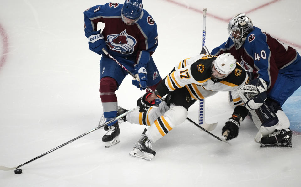 Boston Bruins left wing Nick Foligno, center, reaches for the puck from between Colorado Avalanche defenseman Devon Toews, left, and goaltender Alexandar Georgiev during the first period of an NHL hockey game Wednesday, Dec. 7, 2022, in Denver. (AP Photo/David Zalubowski)