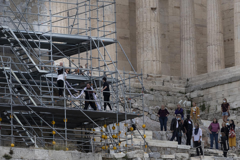 Security staff try to take a banner from protesters on scaffolding at the Acropolis hill, in Athens, Greece, Sunday, Oct. 17, 2021. Three people attempted to hang a banner from the Acropolis in Athens Sunday morning in protest at the upcoming Beijing Winter Olympics but were arrested before completing their mission. (AP Photo/Yorgos Karahalis)