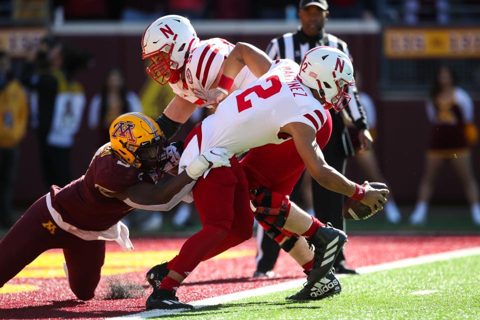 Nebraska quarterback Adrian Martinez tries to get away from Minnesota's Esezi Otomewo in the Huskers' 30-23 loss in Minneapolis on Saturday.