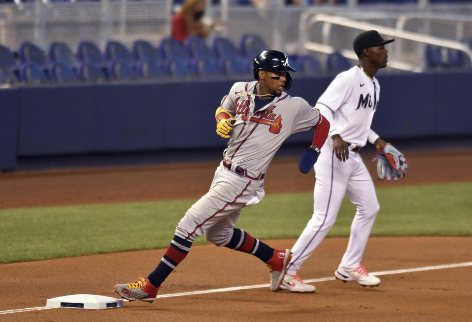 Atlanta Braves' Ronald Acuna Jr., left, advances third base as Miami Marlins' Jazz Chisholm Jr. looks on during the first inning of a baseball game, Sunday, June 13, 2021, in Miami. (AP Photo/Jim Rassol)