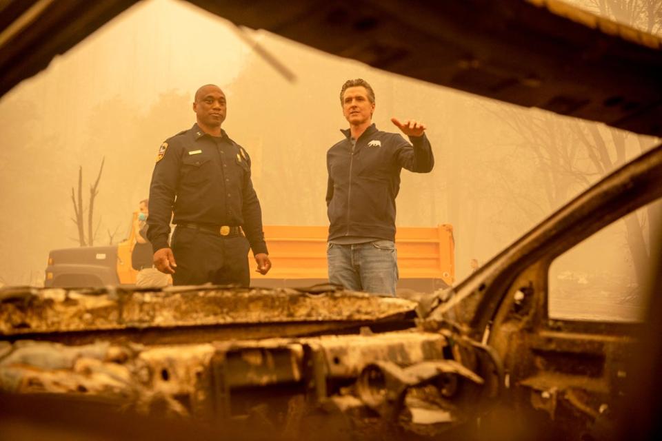 California Governor Gavin Newsom (R) looks at a burned vehicle alongside Assistant Region Chief for Cal Fire Curtis Brown (L) in downtown Greenville on Saturday (AFP via Getty Images)