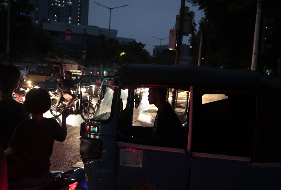 A three-wheeled motorized taxi driver is silhouetted by the lights from incoming traffic as he is stuck in traffic during a power outage in Jakarta, Indonesia, Sunday, Aug. 4, 2019. Indonesia's sprawling capital and other parts of Java island have been hit by a massive power outage affecting millions of people. (AP Photo/Dita Alangkara)