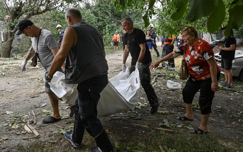 Workers carry a bag containing a body of a dead local resident at a site of a building damaged by a Russian missile strike in Zaporizhzhia