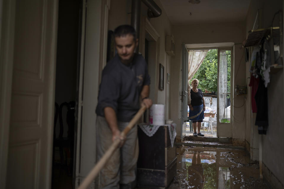 Georgia Sirtarioti, 76, stands as her son Apostolis Sirtariotis, 47, clears muddy water from their flooded home in the storm-hit city of Volos, Greece, where power and water outages remained in some districts, on Friday, Sept. 29, 2023. Bad weather has eased in central Greece leaving widespread flooding and infrastructure damage across the farming region that has been battered by two powerful storms in less than a month. (AP Photo/Petros Giannakouris)