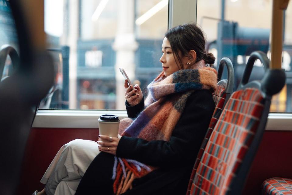 side view of young businesswoman texting with mobile phone while drinking coffee on the bus passenger commuting by public transport female student connecting on social media via smartphone on the train