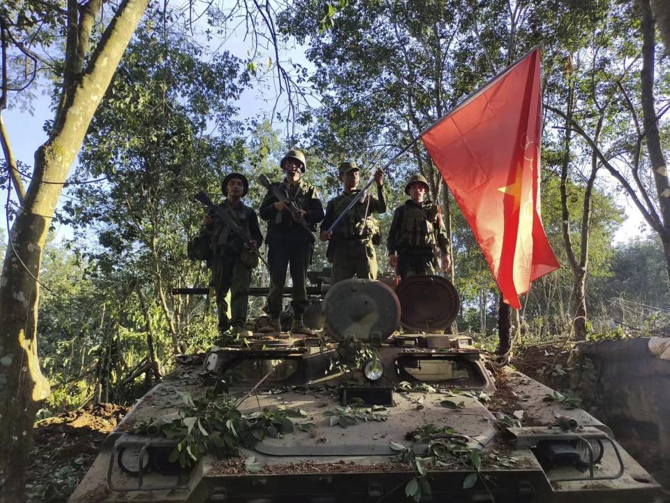 Members of the Myanmar National Democratic Alliance Army hold the group's flag as they pose for a photograph on a captured army armored vehicle in Myanmar, Saturday Oct. 28, 2023. The leader of Myanmar’s army-installed government said the military will carry out counter-attacks against a powerful alliance of ethnic armed groups that has seized towns near the Chinese border in the country’s northeastern and northern regions, state-run media reported Friday Nov. 3, 2023. ("The Kokang" online media via AP)