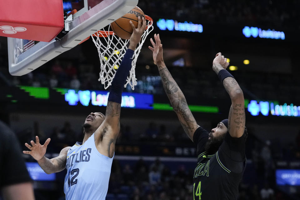 Memphis Grizzlies guard Ja Morant (12) goes to the basket against New Orleans Pelicans forward Brandon Ingram (14) in the first half of an NBA basketball game in New Orleans, Tuesday, Dec. 26, 2023. (AP Photo/Gerald Herbert)