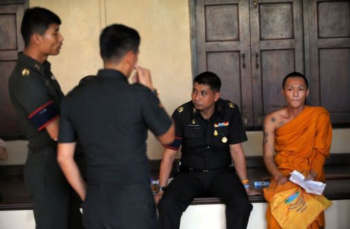 A Thai Buddhist monk sits with soldiers after he was selected as a military recruit - through a lottery system - during a process held at a temple grounds in Bangkok. By law all Thai men who do not volunteer for military service must attend the conscription lottery at least once after they turn 21