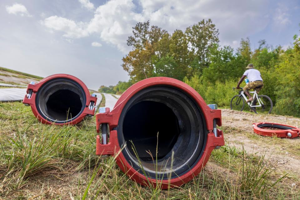 A bike rider passes alongside the pipeline being laid to supply fresh water to Jefferson Parish as salt water slowly moves up the Mississippi River on Wednesday, Oct. 4, 2023, in Marrero, La.