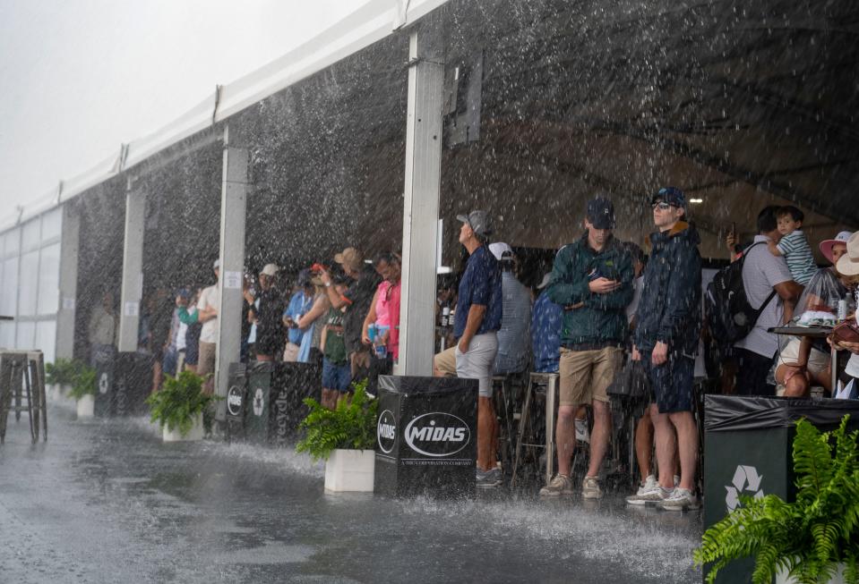 Fans seek shelter behind the 9th green during a thunderstorm at the final round of The Cognizant Classic in The Palm Beaches at PGA National Resort & Spa on March 1, 2024 in Palm Beach Gardens, Florida.