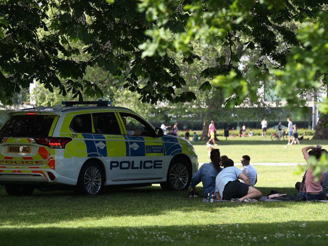 Police officers in a patrol car move sunbathers on in Greenwich Park: PA