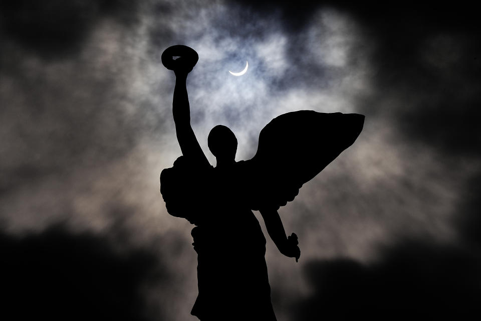 The moon makes its way in front of the sun during a total solar eclipse framed above the angel atop the Princes' Gates, in Toronto, Monday, April 8, 2024. THE CANADIAN PRESS/Frank Gunn