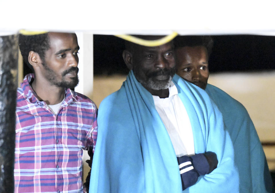 Migrants stand on the Open Arms rescue ship before disembarking on the Sicilian island of Lampedusa, southern Italy, Tuesday, Aug. 20, 2019. Italian prosecutor Luigi Patronaggio has ordered the seizure of a migrant rescue ship and the immediate evacuation of more than 80 migrants remaining on board, capping dramatic developments that saw 15 migrants jump into the sea in a desperate bid to reach land and the Spanish government dispatch a Naval ship on a long journey to resolve the escalating crisis. (AP Photo/Salvatore Cavalli)