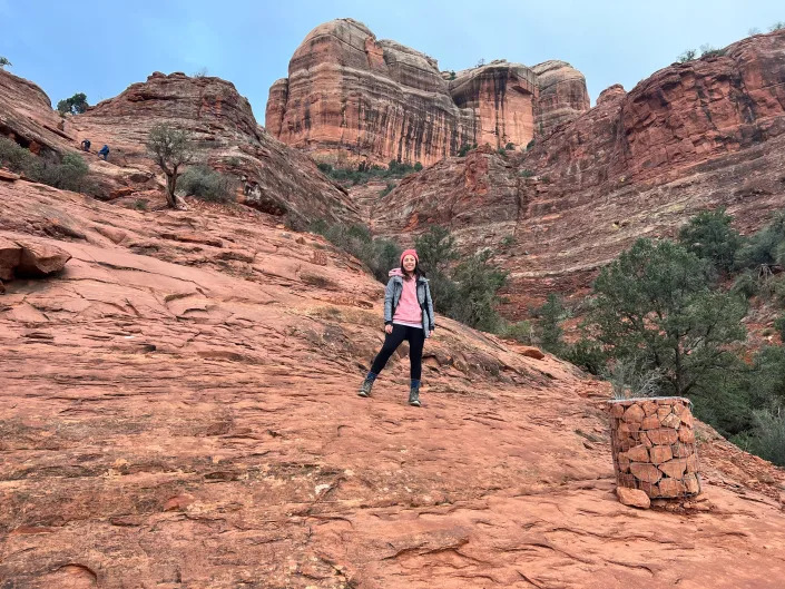 A woman standing on a red rock formation in Arizona.