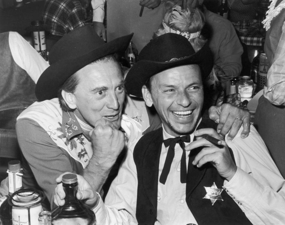 <p>Douglas and Frank Sinatra dressed up in western-themed costumes for a party at the Moulin Rouge in Paris. </p>