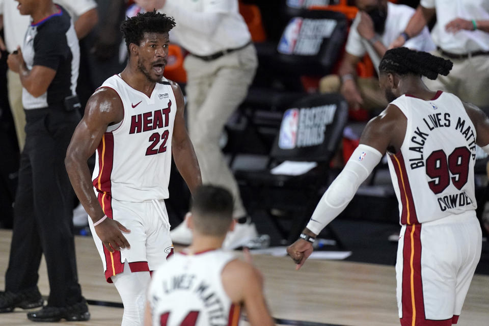 Miami Heat's Jimmy Butler (22), Tyler Herro, bottom center, and Jae Crowder (99) celebrate a game tying basket by Butler late in the second half of an NBA conference final playoff basketball game against the Boston Celtics on Tuesday, Sept. 15, 2020, in Lake Buena Vista, Fla. (AP Photo/Mark J. Terrill)