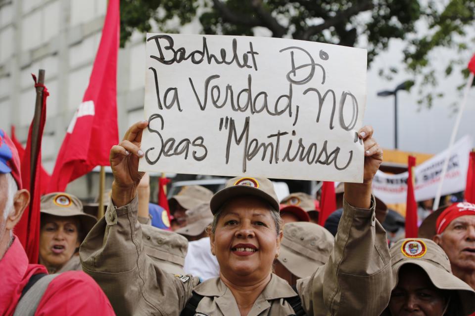 A member of the Bolivarian militia holds up a sign with a message that reads in Spanish: "Bachelet tell the truth" during a protest against Michelle Bachelet, the U.N. high commissioner for human rights, in Caracas, Venezuela, Saturday, July 13, 2019. Bachelet recently published a report accusing Venezuelan officials of human rights abuses, including extrajudicial killings and measures to erode democratic institutions. (AP Photo/Leonardo Fernandez)