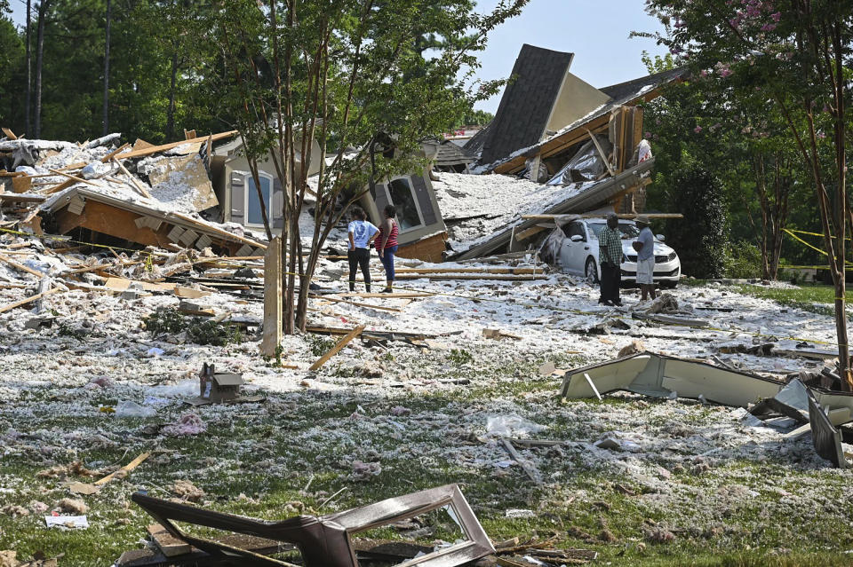 People stand near the remains of a $3 million home on Lake Norman that collapsed in Mooresville, N.C., on Tuesday, Aug. 22, 2023. (Melissa Melvin-Rodriguez/The Charlotte Observer via AP)