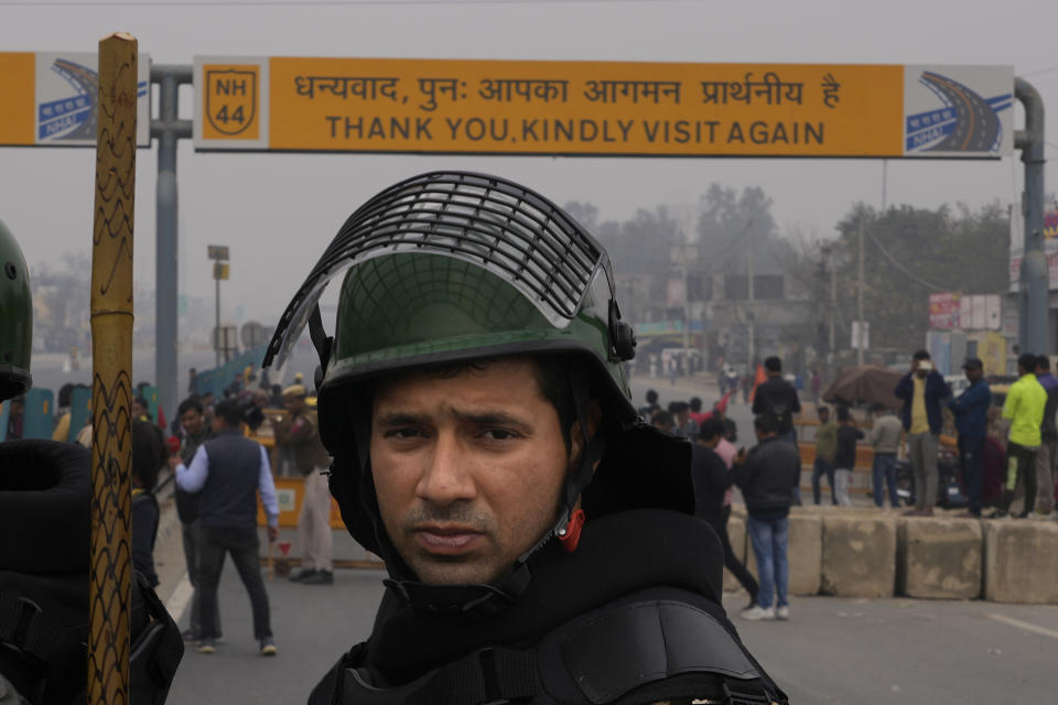 A Delhi police person in riot gear guards a major highway at Singhu near New Delhi to stop thousands of protesting farmers from entering the capital, India, Tuesday, Feb.13, 2024. Farmers, who began their march from northern Haryana and Punjab states, are asking for a guaranteed minimum support price for all farm produce. (AP Photo/Manish Swarup)