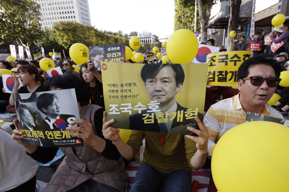 FILE- In this Oct. 12, 2019, file photo, pro-government supporters hold signs with pictures of Justice Minister Cho Kuk, before a rally supporting Cho in front of Seoul Central District Prosecutors' Office in Seoul, South Korea. The letters read "Reform the Prosecution," and "Protect Cho Kuk." South Korean prosecutors have summoned the country’s former justice minister as they expand an investigation into corruption allegations surrounding his family that sparked huge protests. (AP Photo/Lee Jin-man, File)