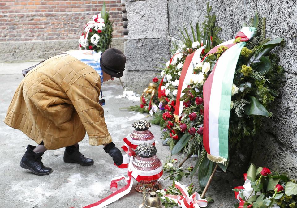 A survivor adjusts a ribbon on a wreath at the 'Wall of Death' in the former Nazi German concentration and extermination camp Auschwitz in Oswiecim