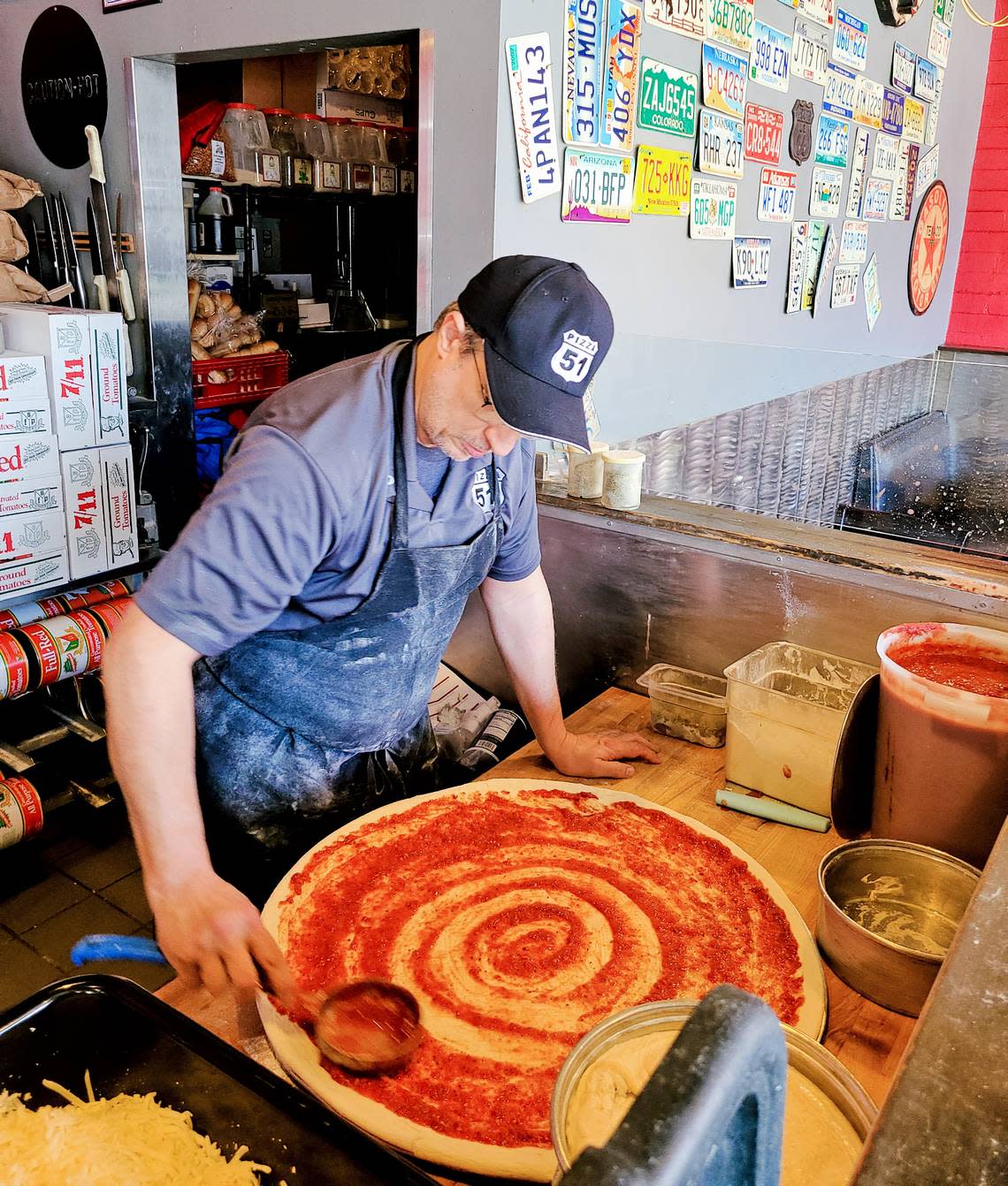 Pizza 51 owner Jason Pryor prepares a pizza to slide into the oven.