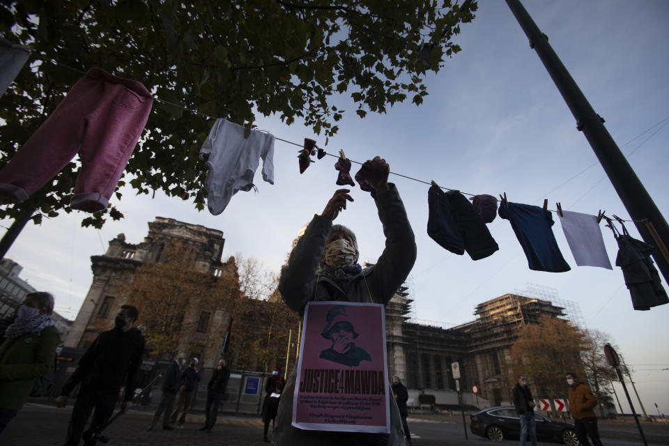 FILE - In this Monday, Nov. 23, 2020 file photo, a woman hangs a piece of children's clothing on a line during a solidarity event for Mawda Shawri at the courthouse in Brussels. A police officer was handed a one-year suspended prison sentence Friday, Feb. 12, 2021 following the shooting death of a two-year-old toddler who was in a van during a high-speed chase between police and suspected migrant smugglers seeking to get to Britain. (AP Photo/Virginia Mayo, File)